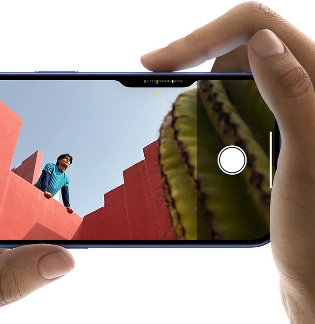 صورة لوحدة التحكم في الكاميرا في iPhone&nbsp;16 تظهر كيف ينزلق الإصبع الأيمن على جانب الهاتف لضبط إعدادات الكاميرا