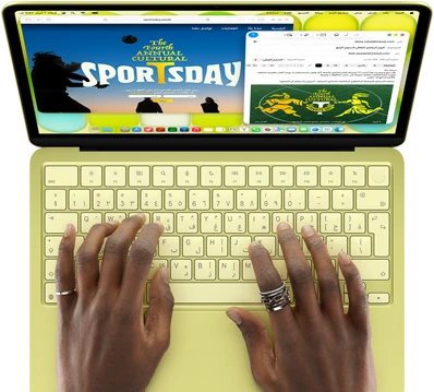 جهاز MacBook Neo، لون أصفر سيتروس، يدان على لوحة المفاتيح، المستخدم يكتب دعوة عبر الإيميل لحضور فعالية رياضية، موقع ويب خاص بالفعالية مفتوح على الجانب