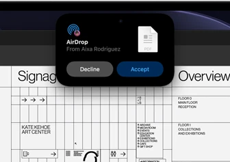 شاشة تعرض Dynamic Island مع طلب إرسال سريع يظهر في نافذة صغيرة فوق ملف Adobe Acrobat مفتوح loading=