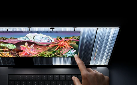 جهاز MacBook Pro مع شاشة PROLED XDR، لون أسود فلكي، مستخدم يغيّر حجم نافذة على الشاشة بطرف إصبعه